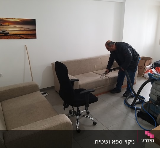 אדם מנקה ספה עם מכונת ניקוי מקצועית